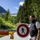 Gregory Logean, président de la commune d'Hérémence devant la barrière qui ferme la route, suite à l'éboulement de roches proche du barrage de la Grande Dixence jeudi 17 juillet. KEYSTONE/JEAN-CHRISTOPHE BOTT